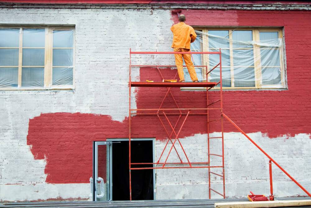 Commercial exterior painting in progress on a brick building with surface preparation and durable finishes by a painter in Bradenton, FL